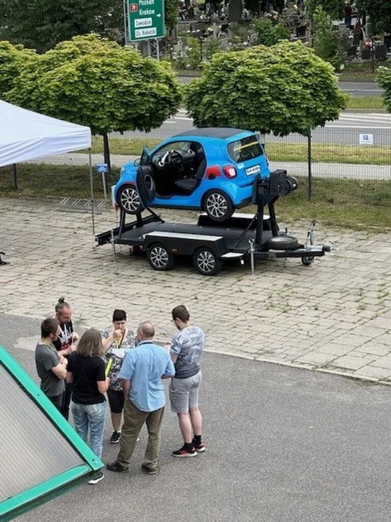 Samochód na podnośniku i grupka osób